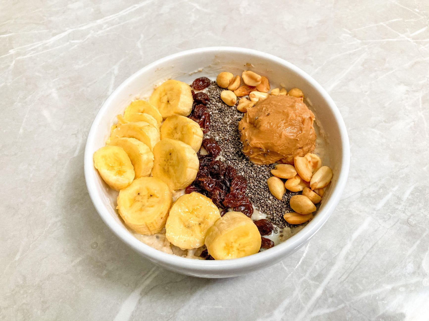 Miska śniadaniowa z bananem, chia, orzeszkami, rodzynkami i masłem orzechowym Miska śniadaniowa z bananem, chia, orzeszkami, rodzynkami i masłem orzechowym
