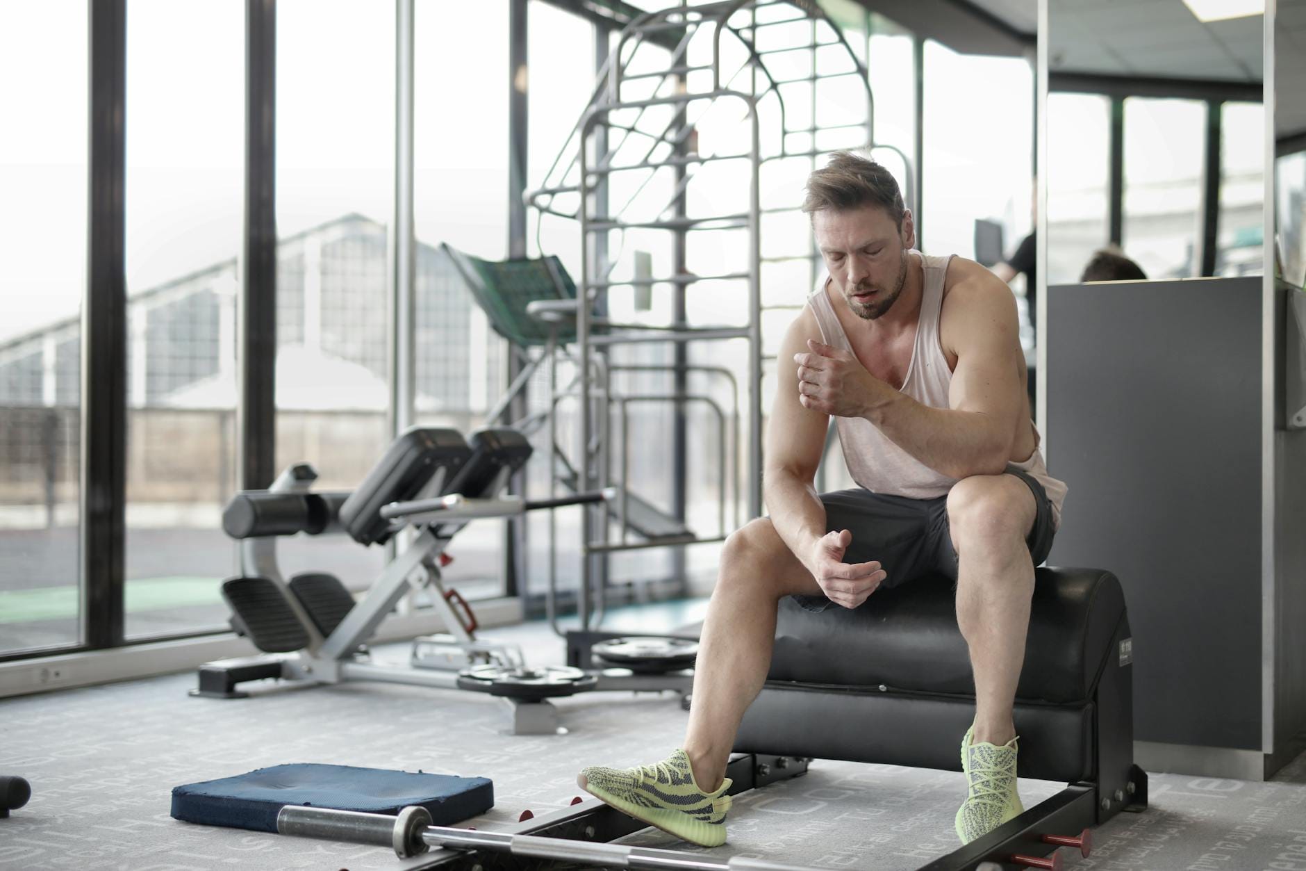 Regeneracja po treningu w domu proste rytuały dla zapracowanych i zabieganych Zmęczony młody sportowiec siedzi na ławce i odpoczywa po treningu