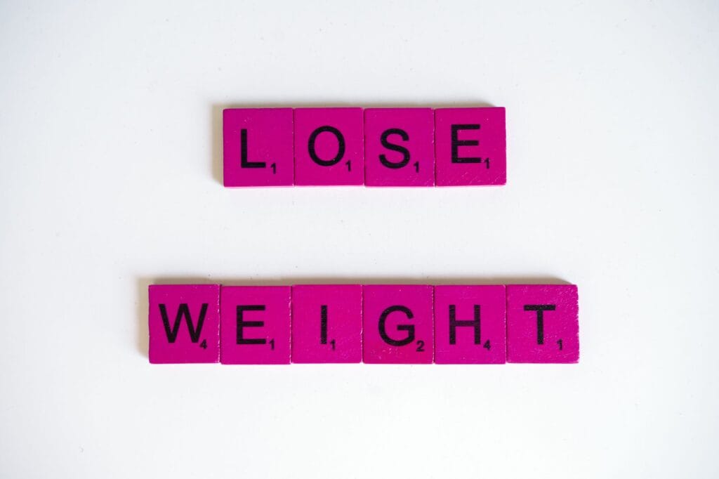 Napis Lose Weight ułożony z płytek Scrabble na białym tle